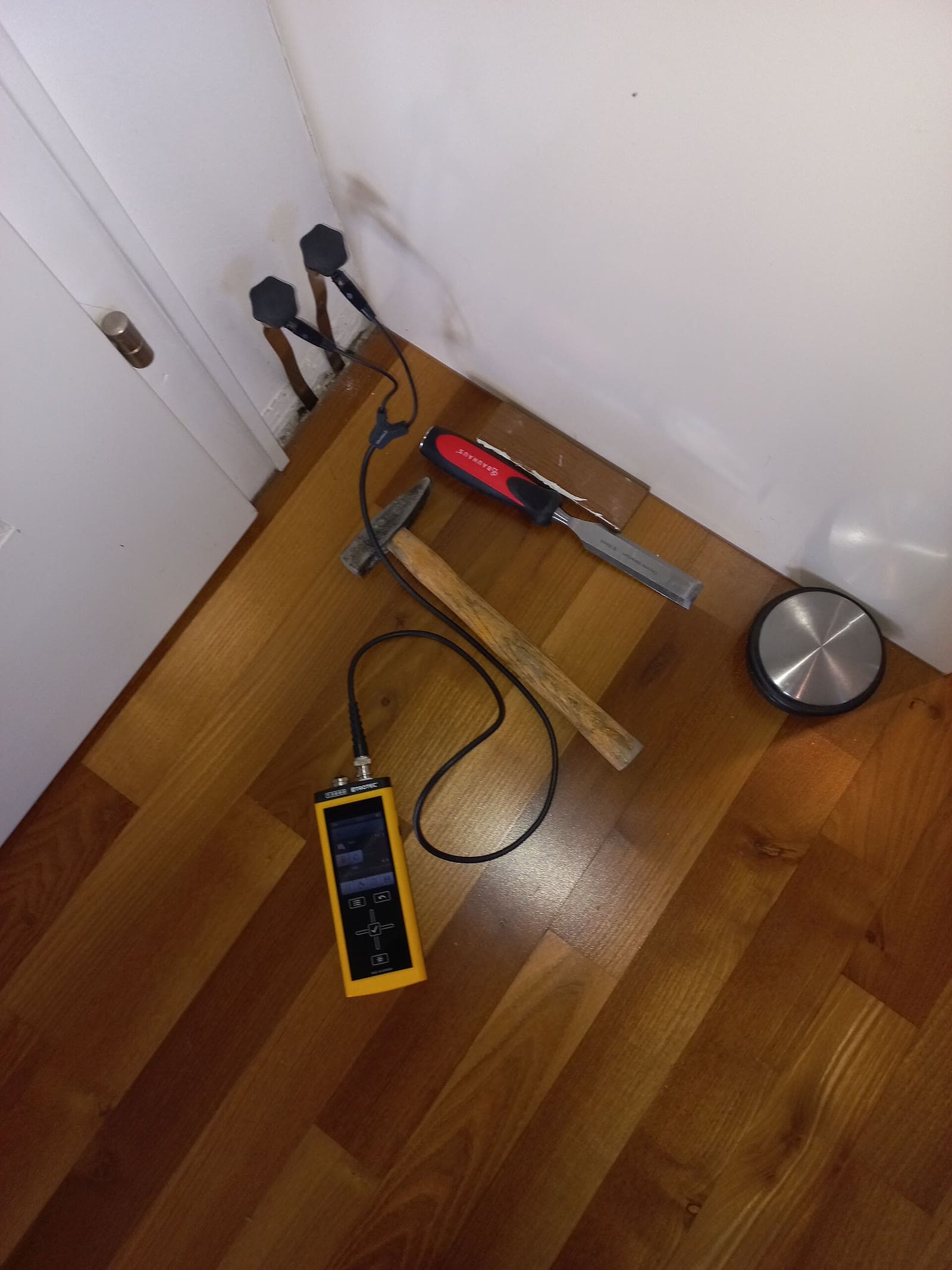 A moisture meter held against a wall.